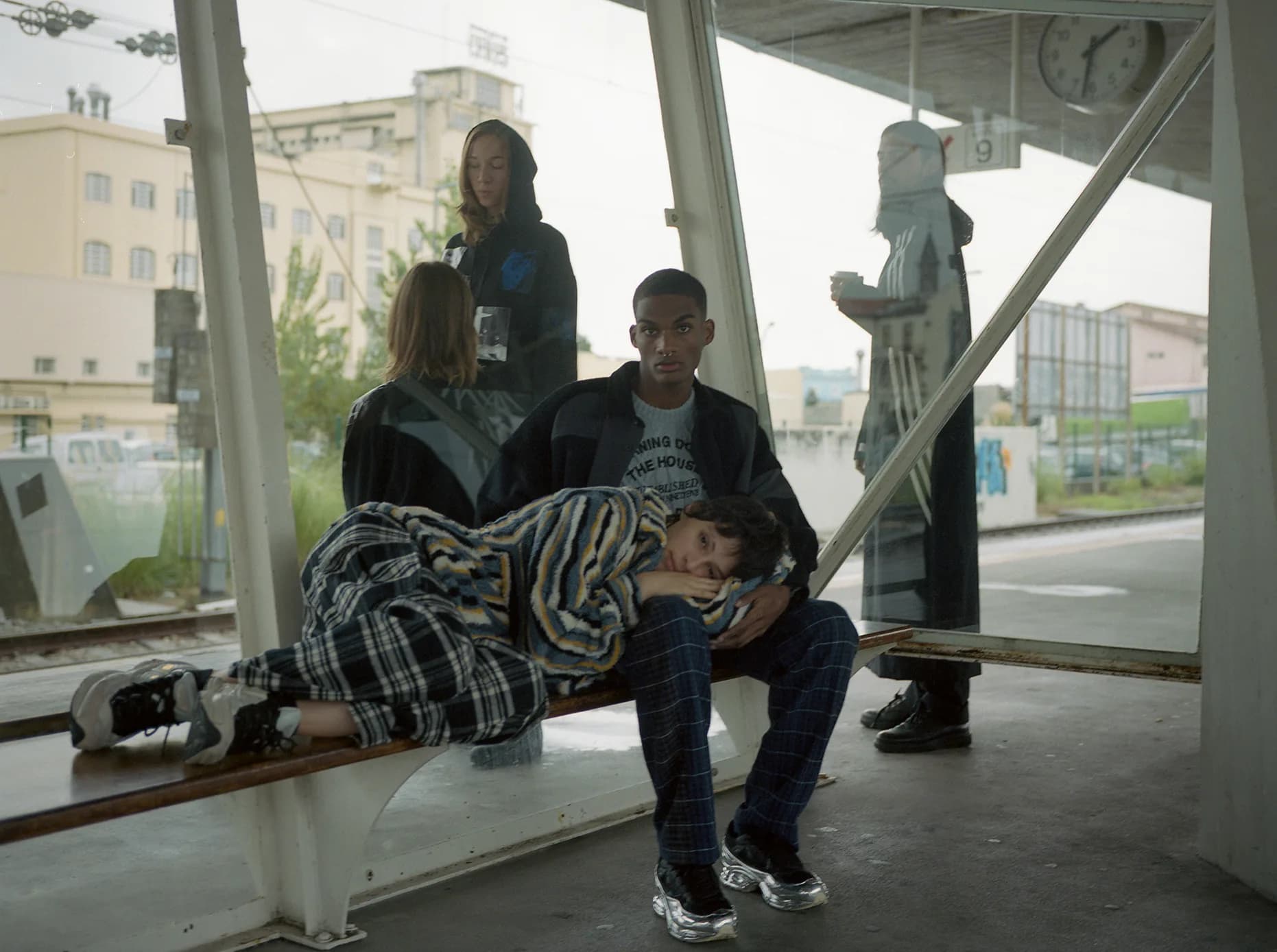 Group scene at a covered bus stop, one figure resting on the bench